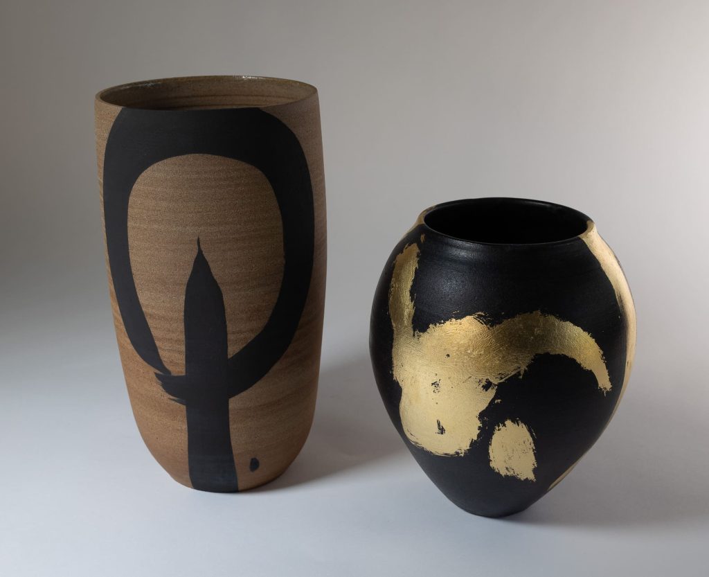 Charlotte Sauvat (Vase, 2025, grès brut, engobe noir et intérieur émaillé, h. 27 x d. 14 cm) et Fabien Mérillon (Vase, 2025, grès émaillé noir et feuille d'or, h. 24,5 x d. 18 cm)